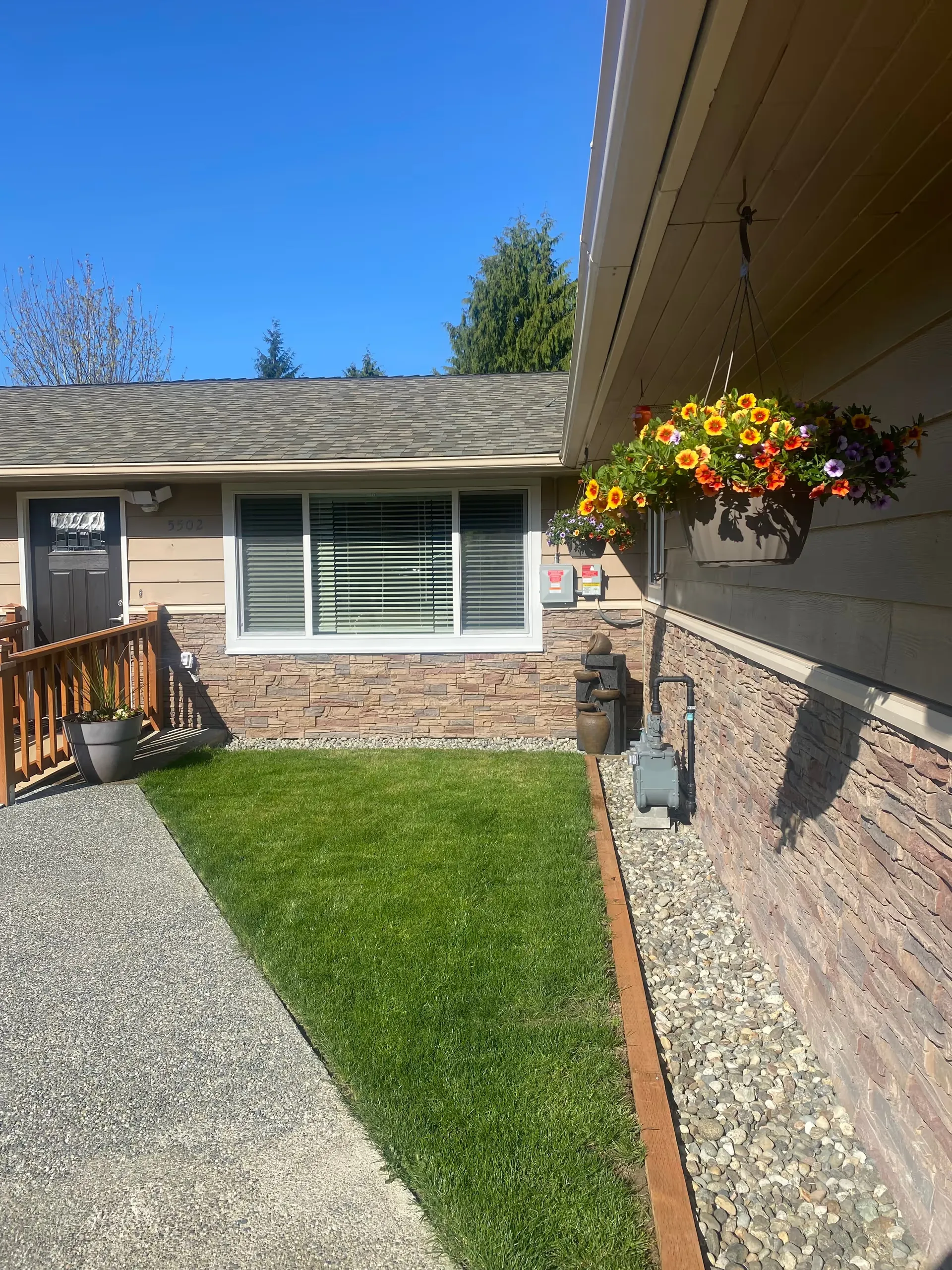 Front of the Ocean View Elderly Care Adult Family Home with hanging flowers and a lawn